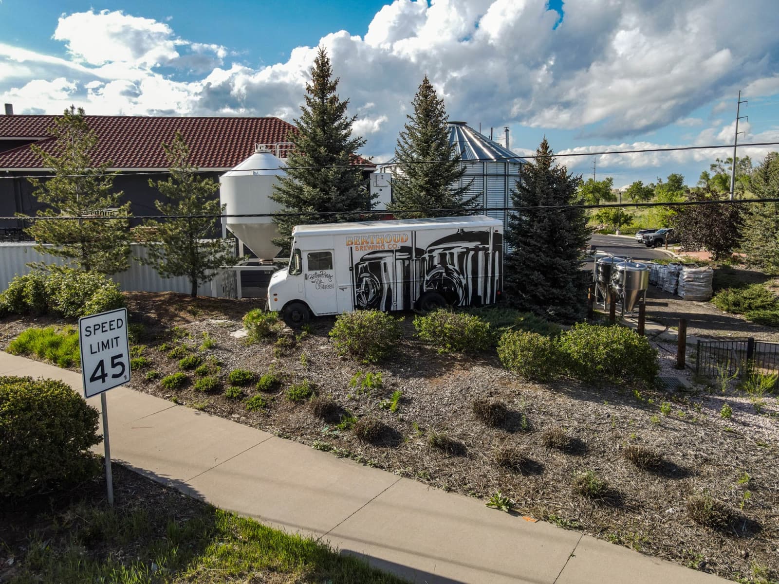 Roadside view of the brewery grounds and grain silo under a big Colorado sky