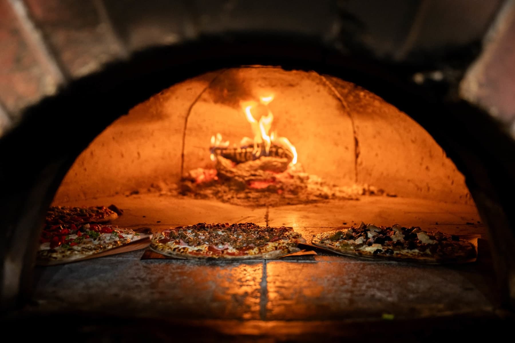 A pizza blistering inside the wood-fired oven