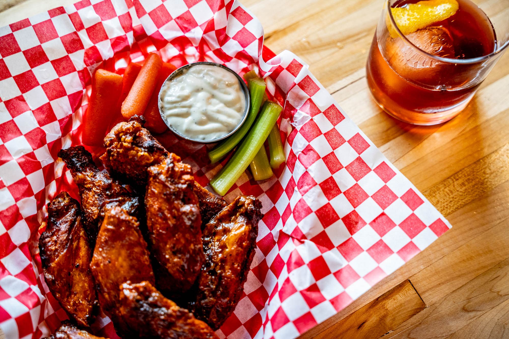 Smoked wings in a checkered basket with celery and ranch
